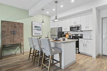 A kitchen with an island and three bar stools
